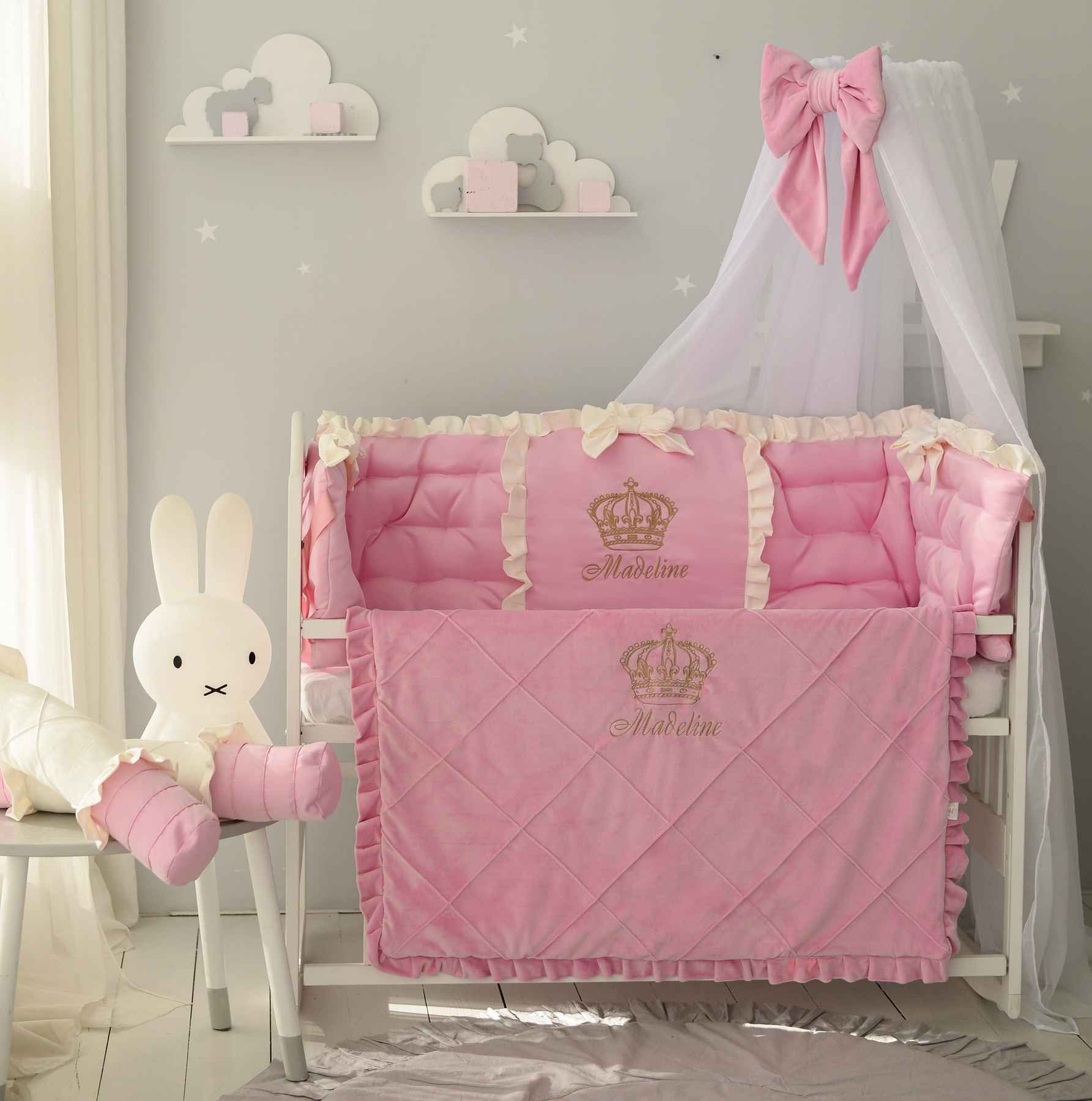 An elegant pink crib bedding set in a soft dusty rose shade, styled in a modern baby's room.