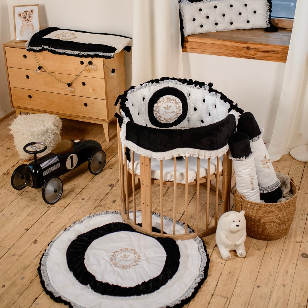Nursery room with wooden crib, round black and white rug, and decorative bedding set.