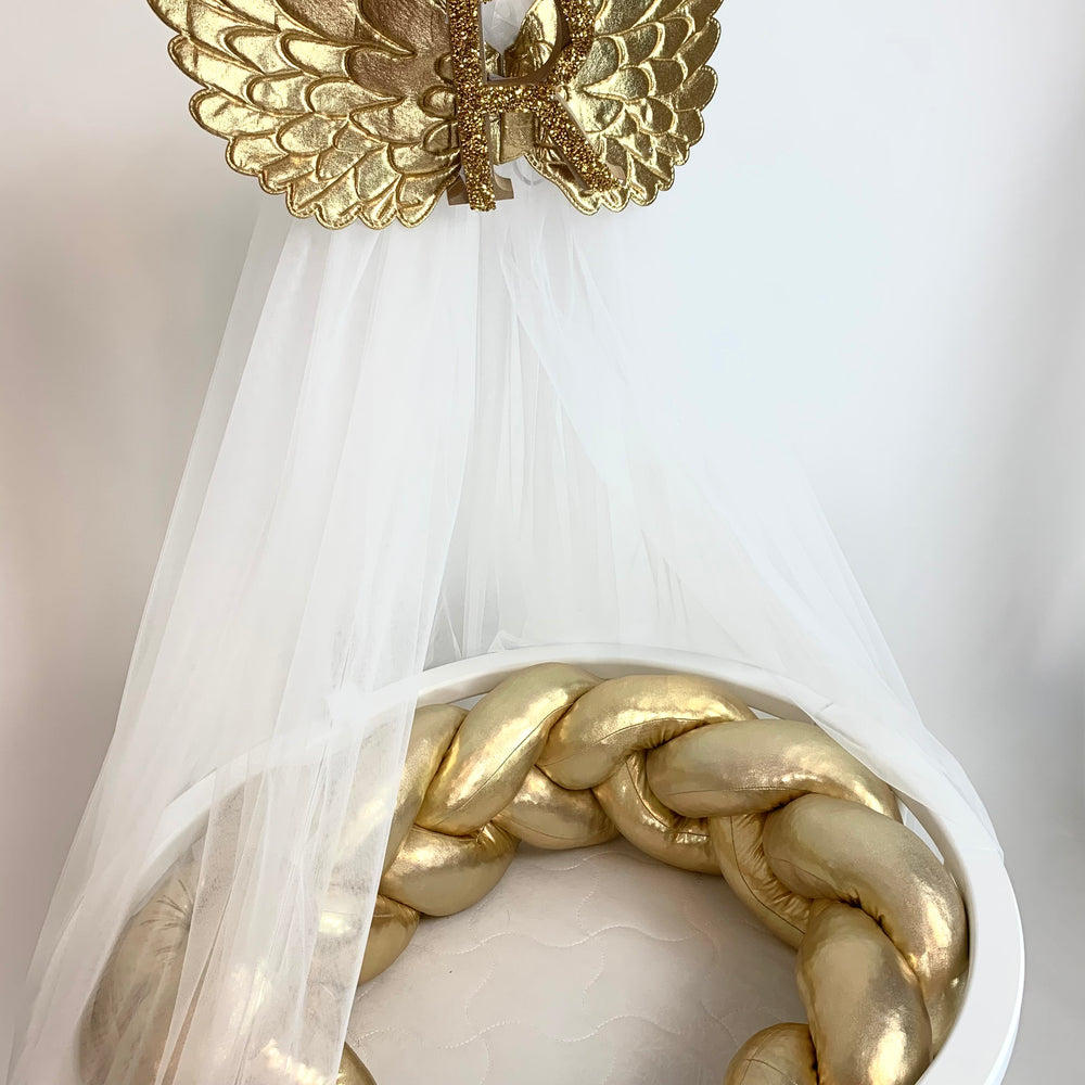 Gold butterfly and braided design of the baby crib against a white background