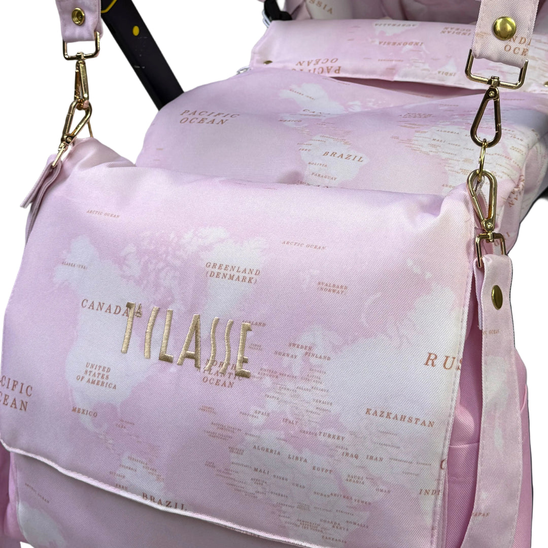 Close-up of pink world map diaper bag with gold ‘1 Classe’ embroidery and gold-tone hardware.