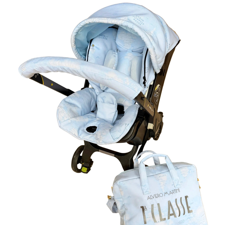 Front angled view of Doona Plus with light blue world map cover set installed, paired with matching diaper bag featuring silver embroidery.