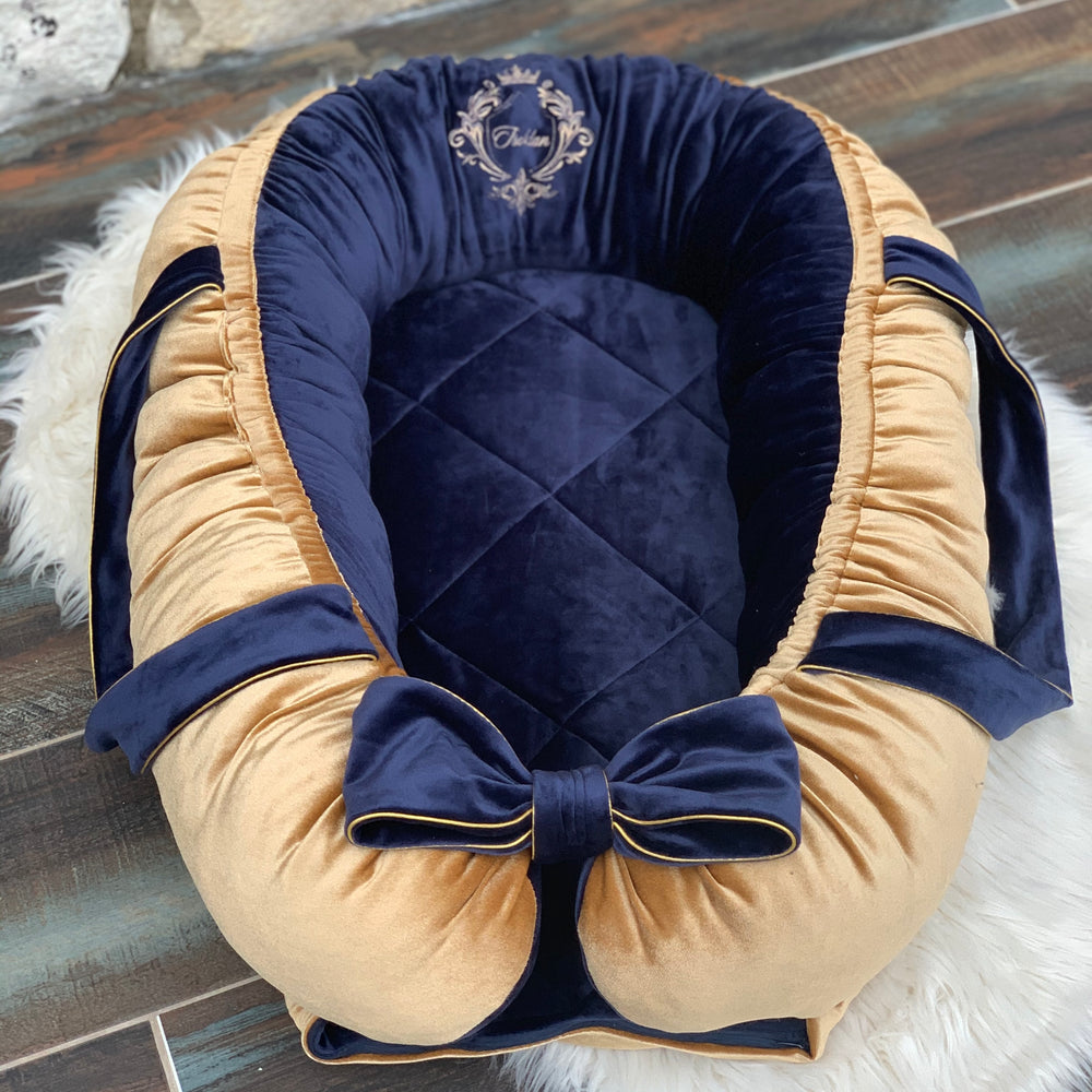 Navy and gold baby nest with a bow on a textured surface