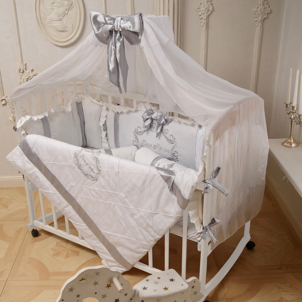 Baby crib with white and gray baby bedding set in a decorated room