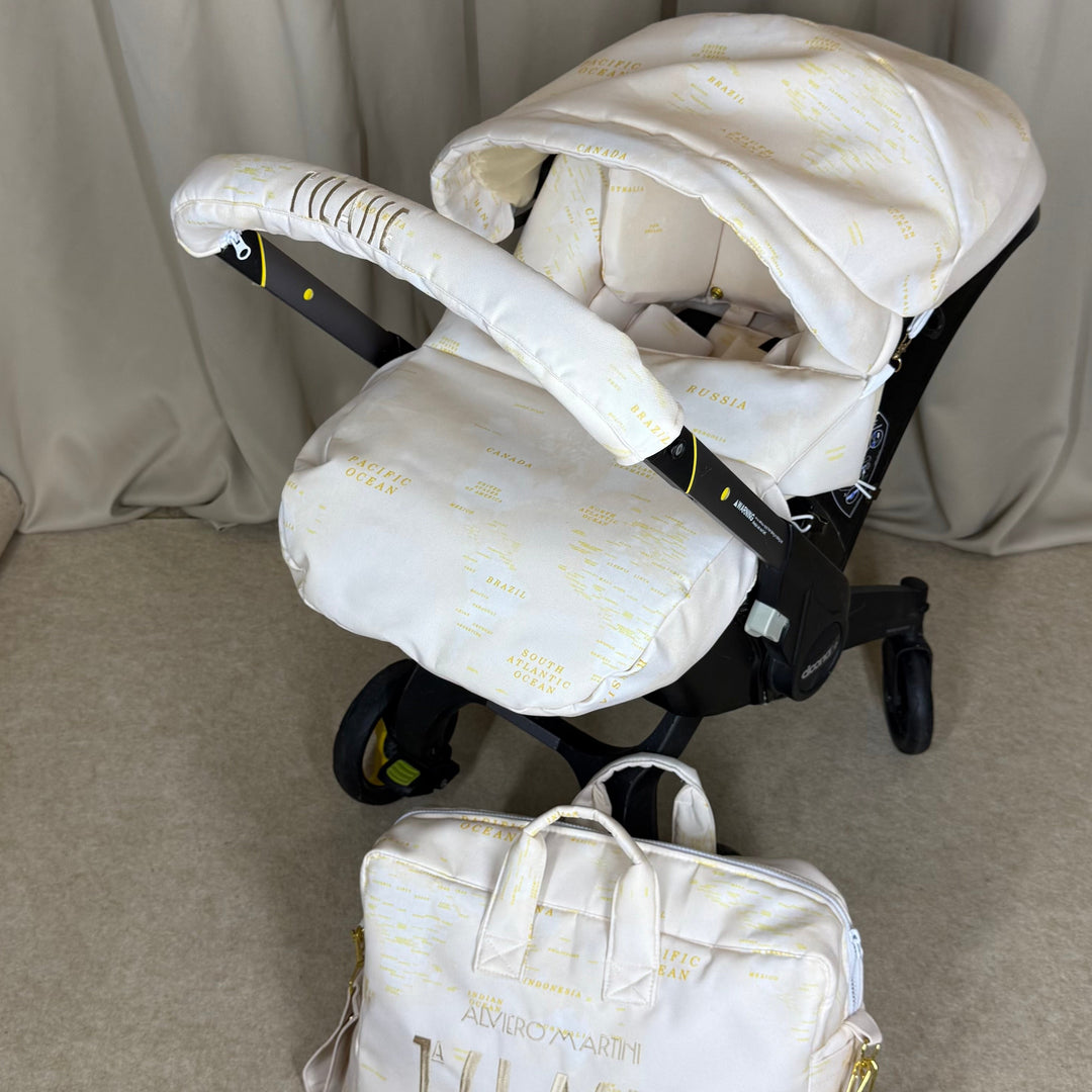 Luxury beige world map cover set with gold map print and matching diaper bag on Doona Plus stroller, styled against soft beige curtains.