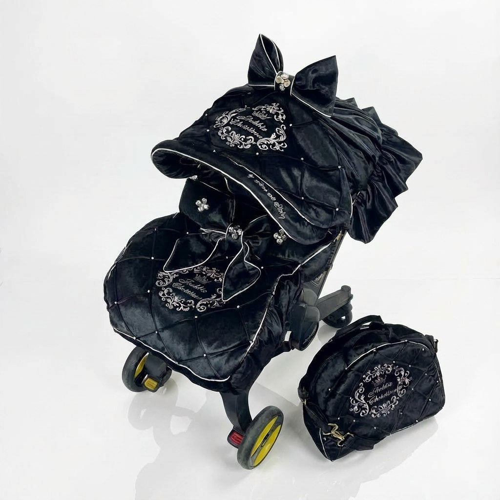 Black decorative stroller cover set installed on a Doona-style car seat, with embroidery, ruffles, bow accent, and matching bag