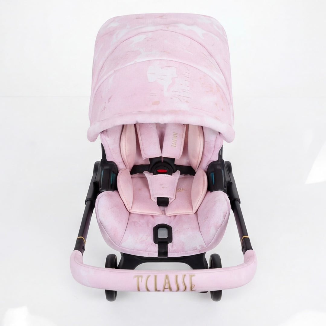 Top view of a pink world map cover set installed on Doona X car seat, featuring padded canopy and embroidered handlebar cover.