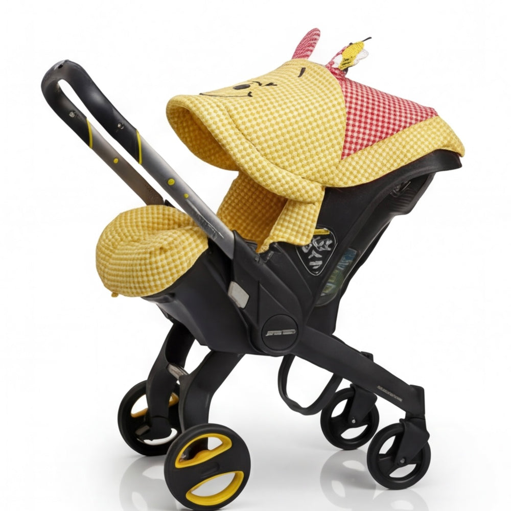 Yellow gingham Doona+ car seat cover set with bear canopy design and red checkered accents, stroller mode, white background.