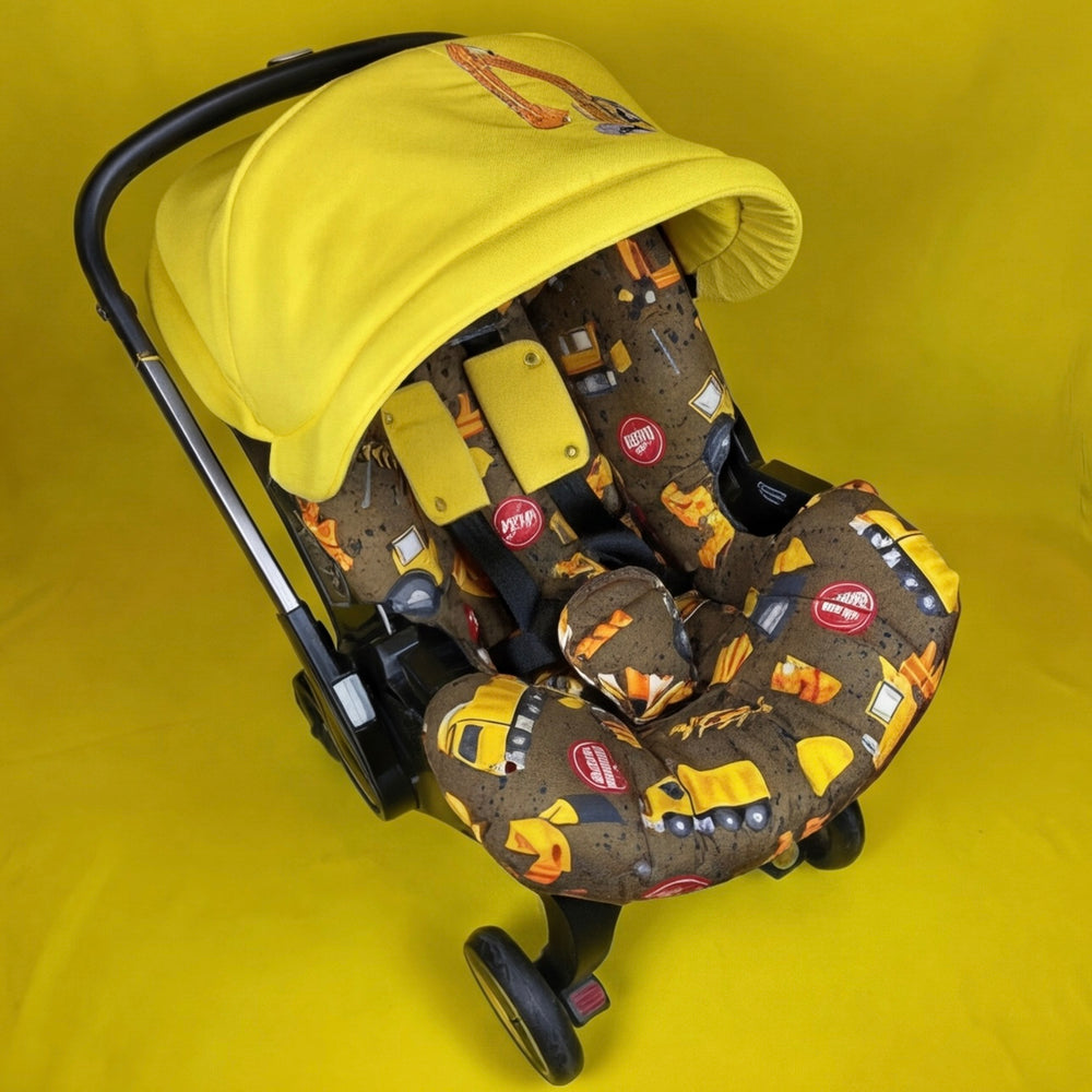 Doona car seat cover set with construction truck print and yellow embroidered canopy.