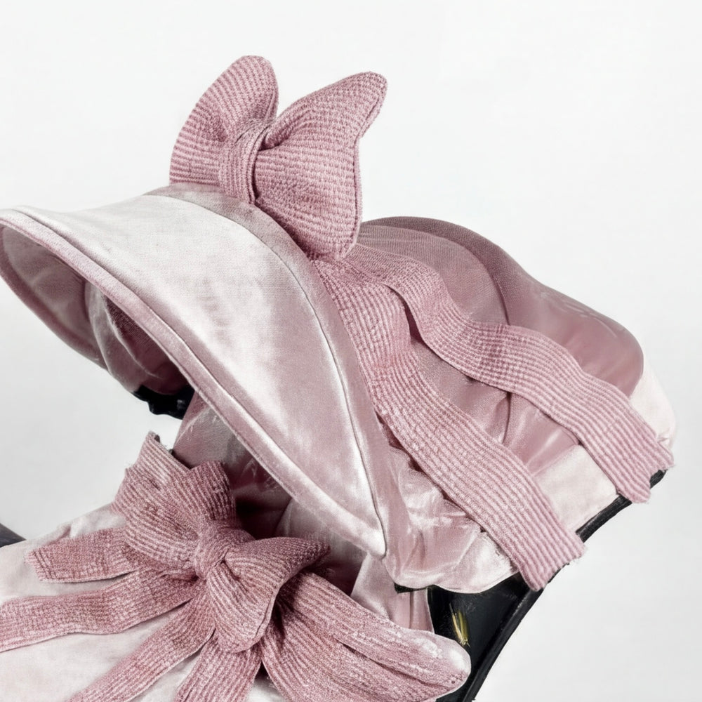 Dusty pink velvet infant car seat canopy featuring a large textured ribbed bow on top, shown in close-up on a light background.