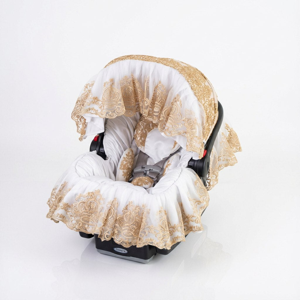 Pink satin baby car seat cover with gathered padding and decorative gold lace trim. The design features a ruffled satin canopy with matching lace overlay and a coordinated padded seat insert, photographed on a light studio background.