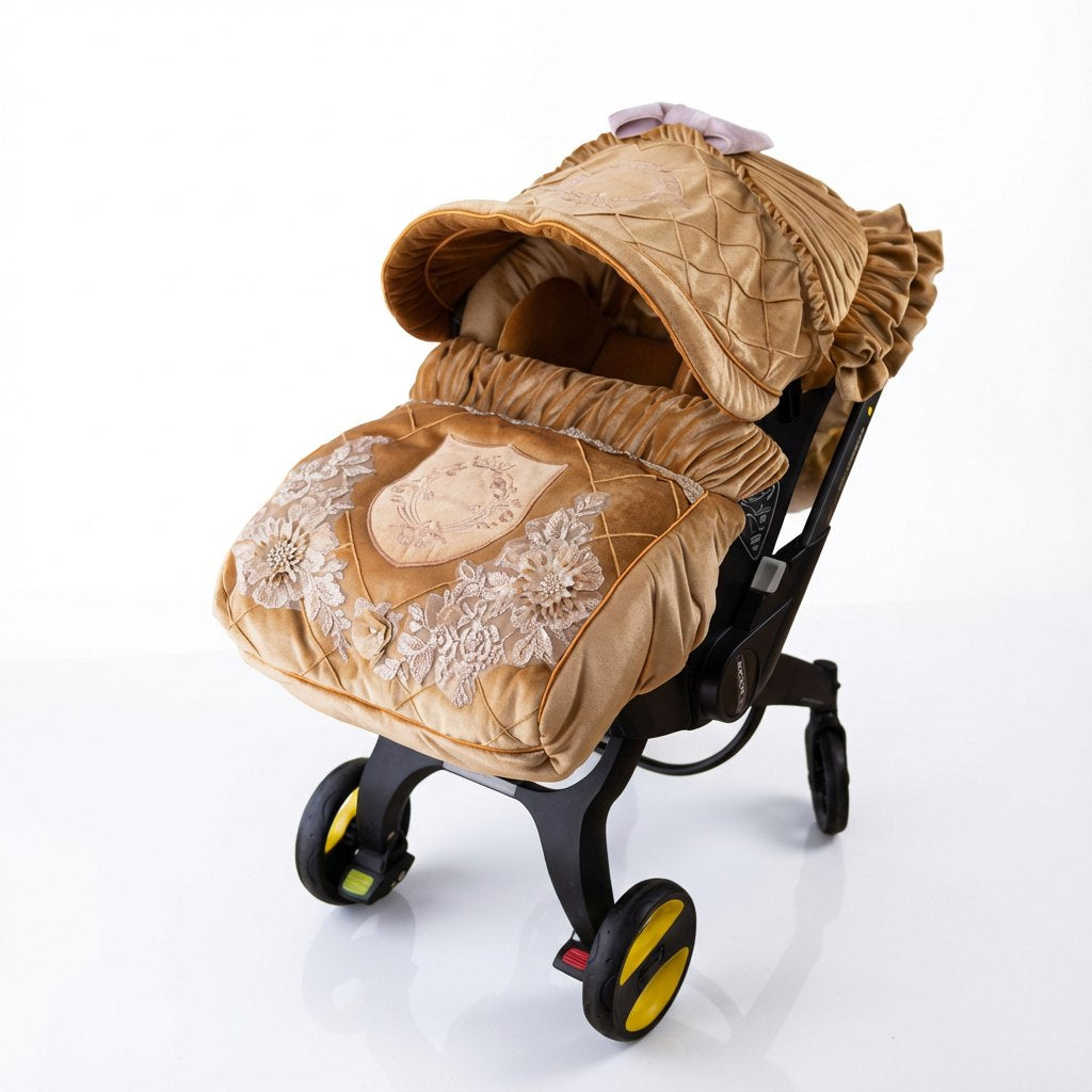 Gold velvet baby car seat cover with pink embroidery and lace details, installed on a car seat on a white background.
