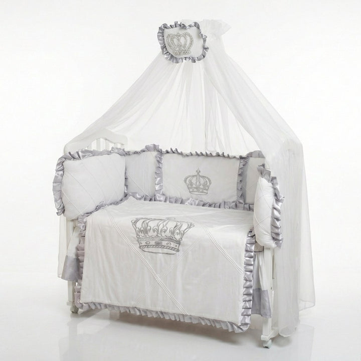 Baby crib set with gray and white bedding featuring crowns on a white background