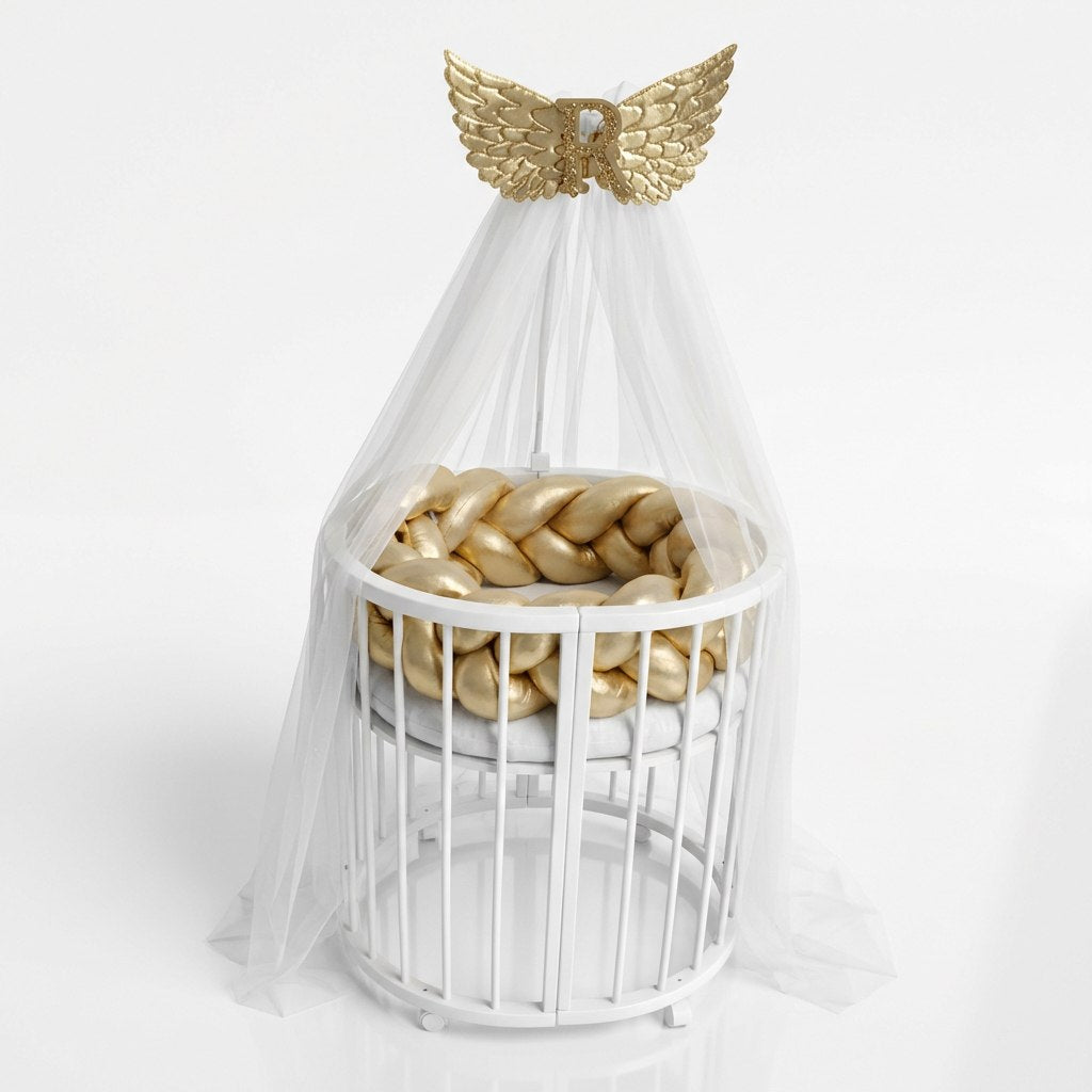 White crib with gold braided bumper and gold angel wings on a white background