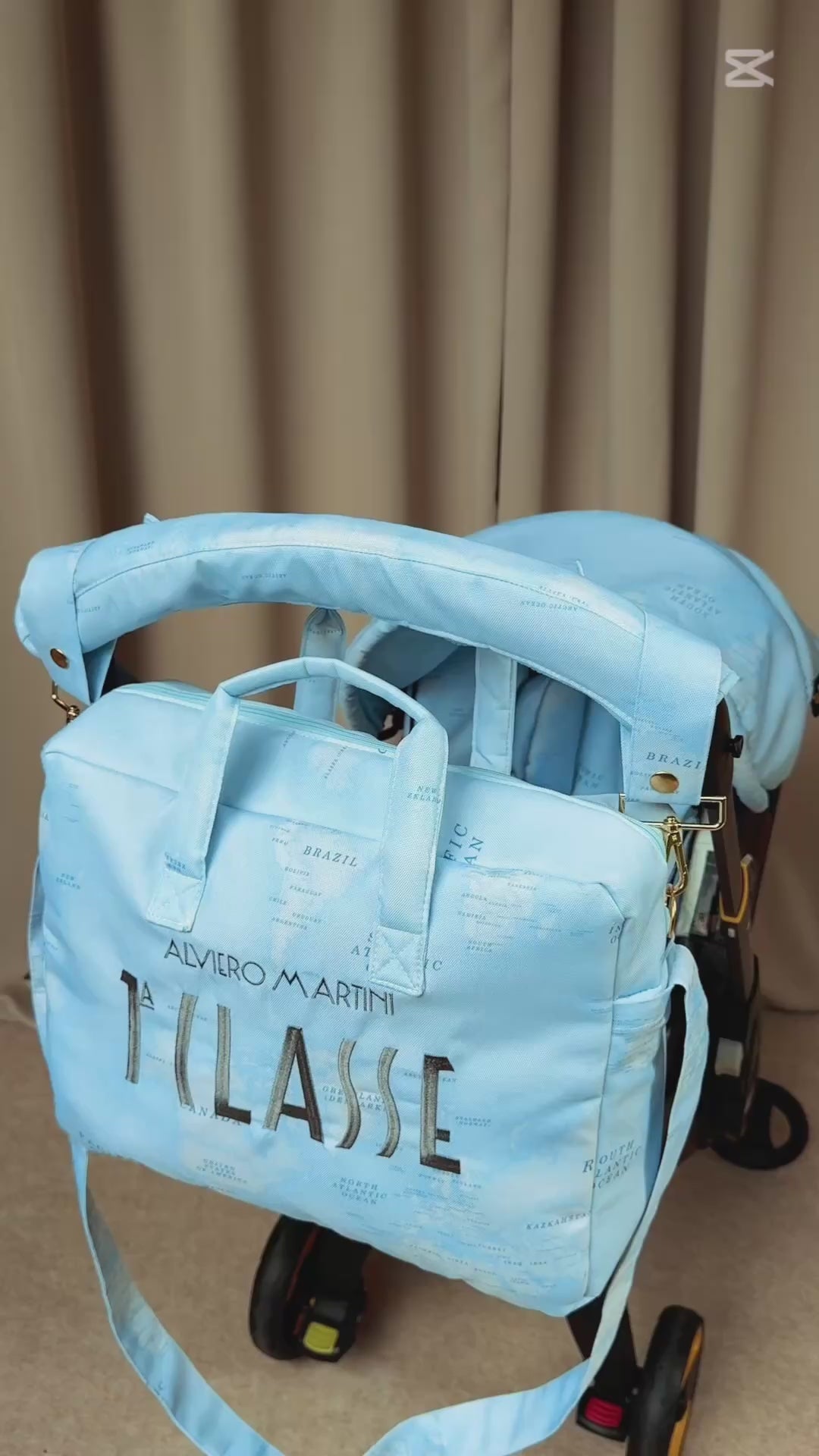 Video of light blue world map stroller cover set with matching diaper bag and silver embroidery.