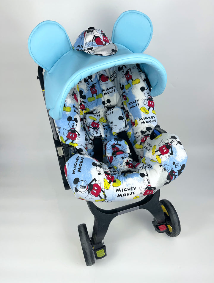 Baby blue car seat cover set with Mickey Mouse print for Doona car seat. Includes replacement hood, shoulder and crotch pads, seat overlay, and blanket. Optional bag available. Perfect for keeping your baby's car seat clean and stylish. Compatible with other car seat types as well.